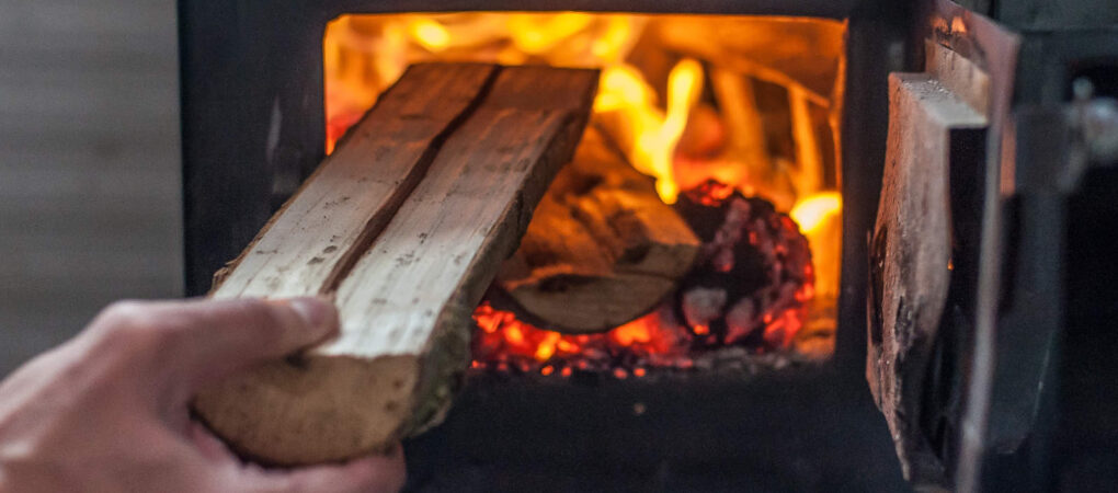 Man putting log to wood burning stove. Close up